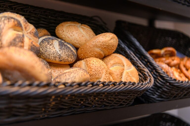 In einer charmanten Backstube erwarten die Besucher prall gefüllte Körbe mit verschiedenen Brötchen und Brezeln, die an die herzliche Gastfreundschaft im Hotel Bodenmais erinnern.