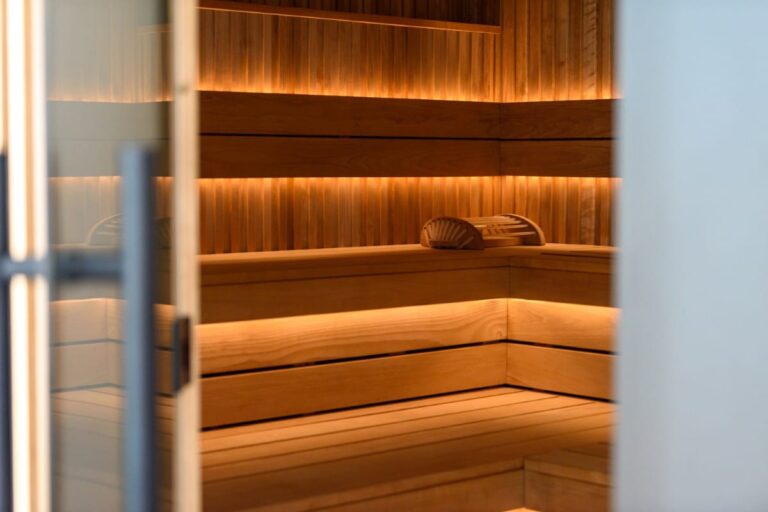 Erleben Sie die ruhige Holzsauna im Hotel Bodenmais mit ihrer warmen Beleuchtung und den zwei bequemen Kopfstützen auf der Sitzbank – ein perfekter Rückzugsort zum Entspannen.