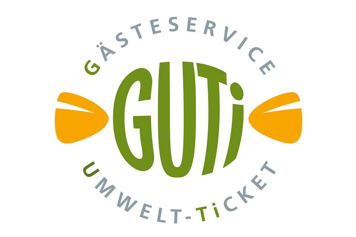 Logo mit „GUTi“ in Grün, umrahmt vom „Gästeservice Umwelt-Ticket“, flankiert von gelben stilisierten Formen. Perfekt für das Hotel Bodenmais, das den Geist der Gastfreundschaft und Nachhaltigkeit im Herzen von Bodenmais einfängt.
